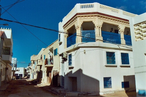 Vue extérieure d'un nouveau logement traditionnel djerbien, avec un balcon bleu élaboré